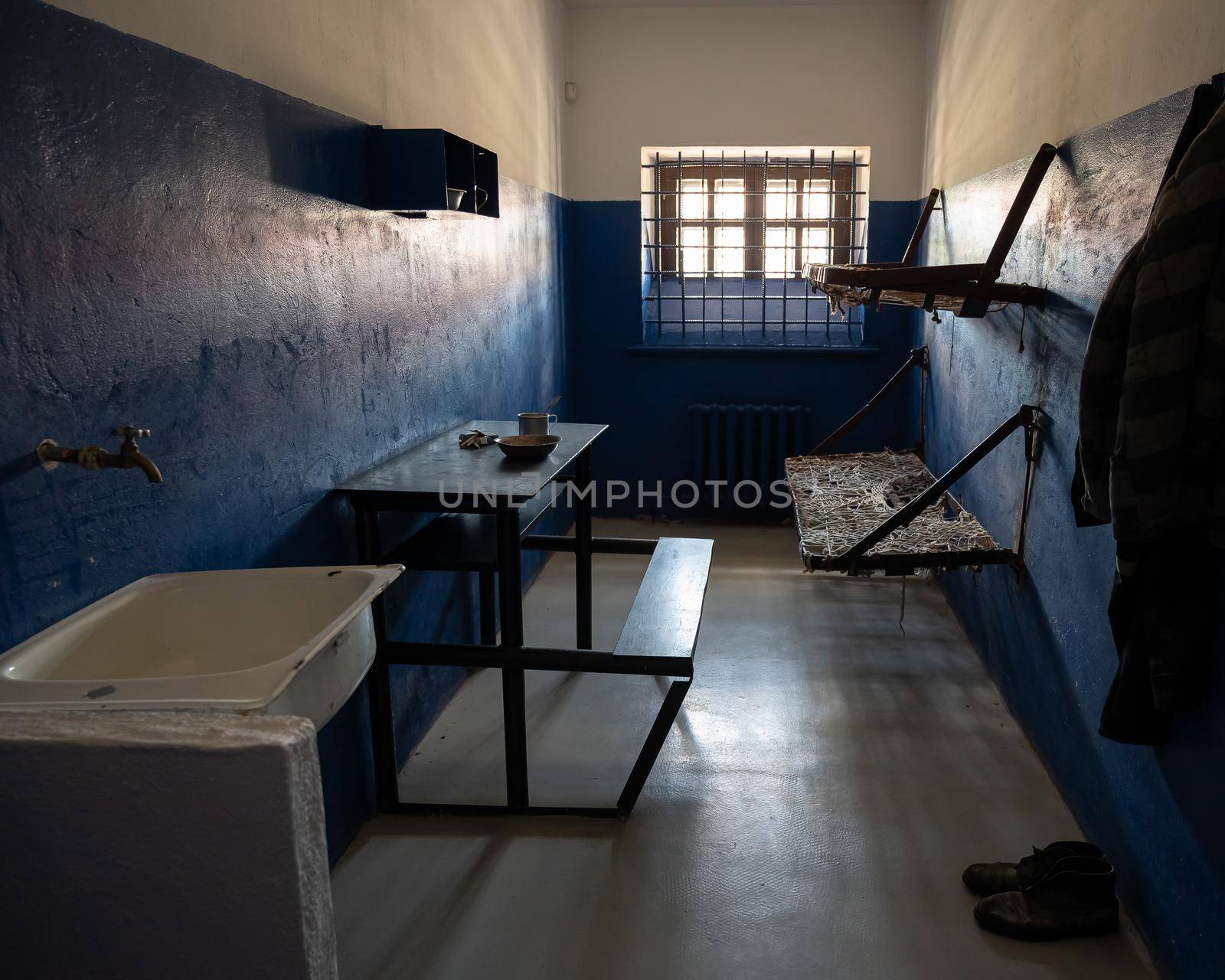 Empty double prison cell with bars on the window.