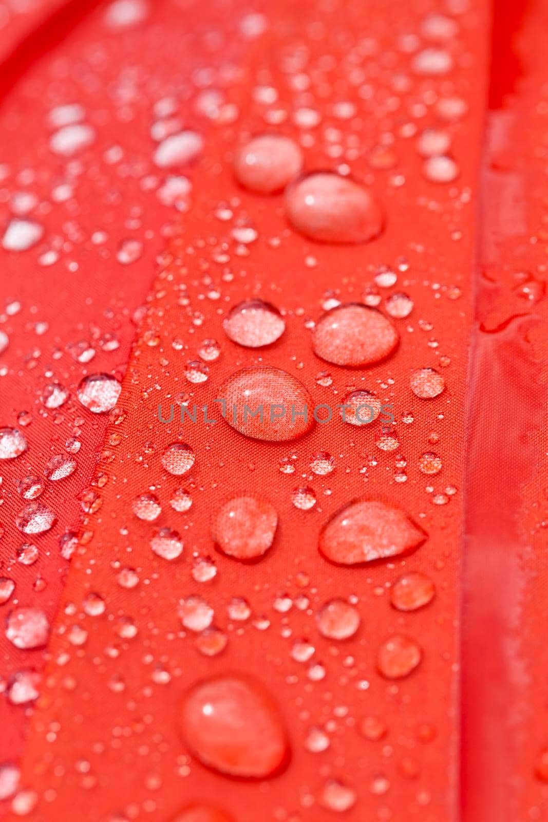 red part of a multi-colored umbrella with water drops in the rain, closeup