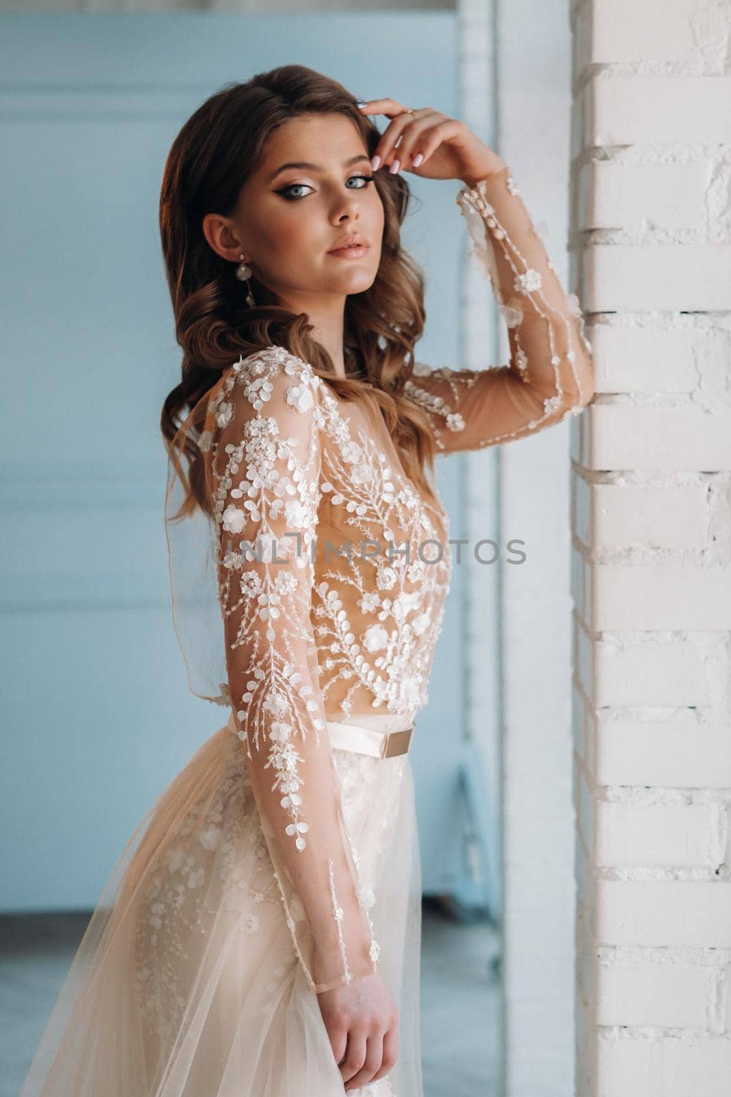 A luxurious bride in a wedding dress in the morning in her interior.