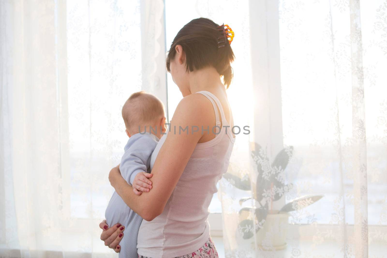 Happy mother holding adorable child baby with sunrise background