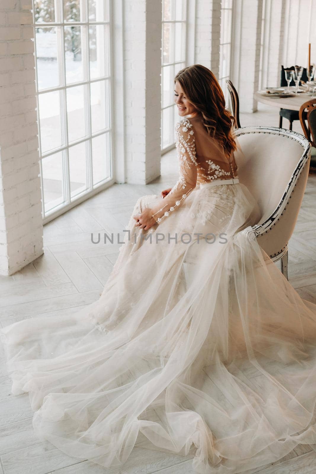 A luxurious bride in a wedding dress in the morning in her interior.