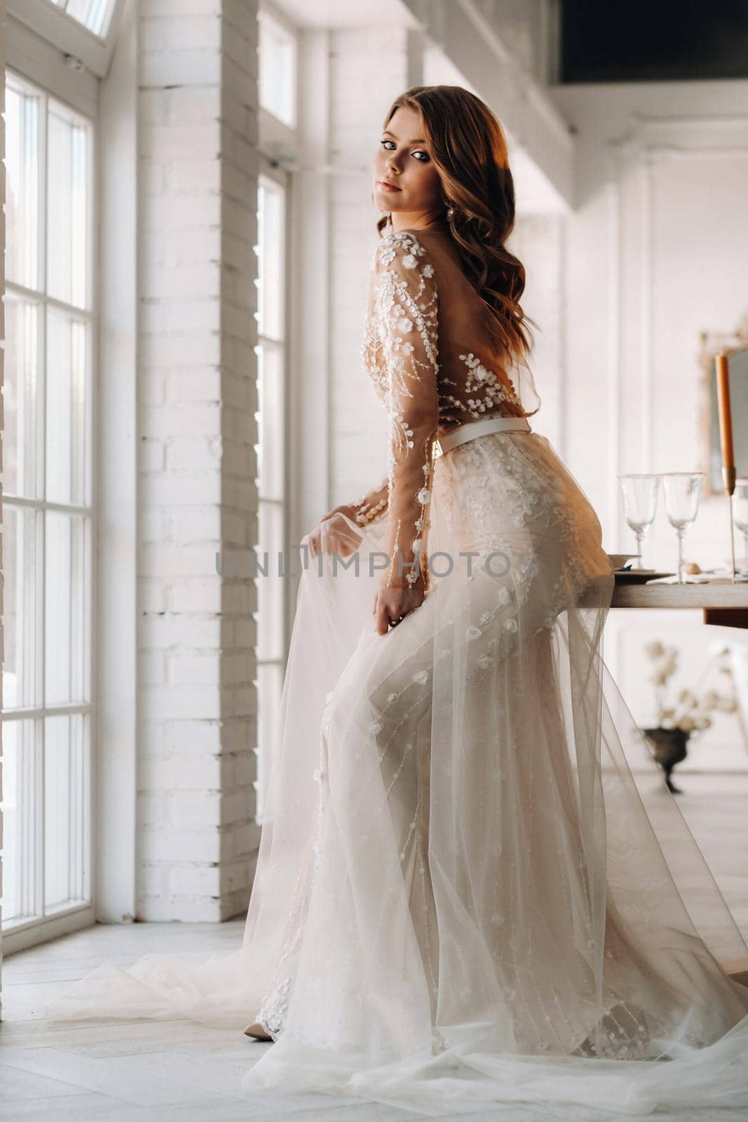 A luxurious bride in a wedding dress in the morning in her interior.