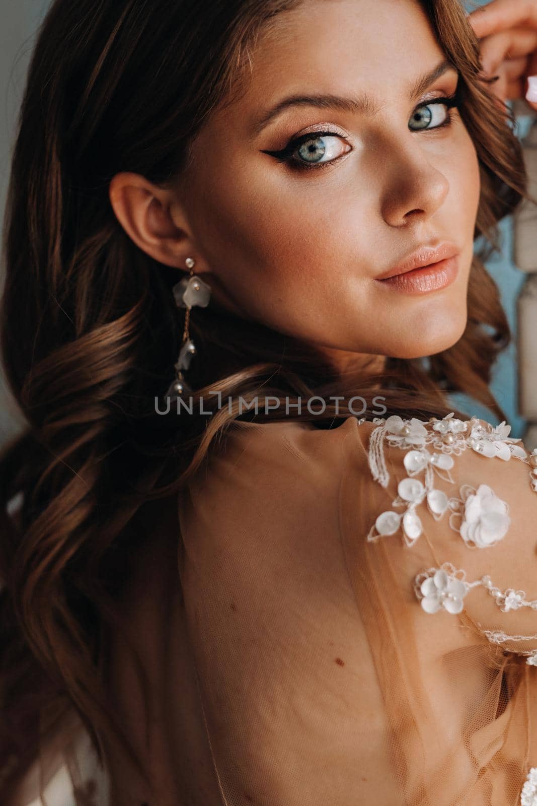 Close-up portrait of a luxurious bride in a wedding dress in the morning in her interior.