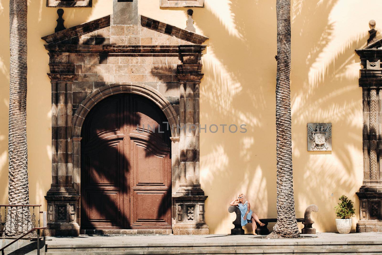 A girl in a blue dress sits on a bench in the old town of Garachico on the island of Tenerife on a Sunny day.A tourist walks in the old town on the island of Tenerife Canary Islands.Spain.