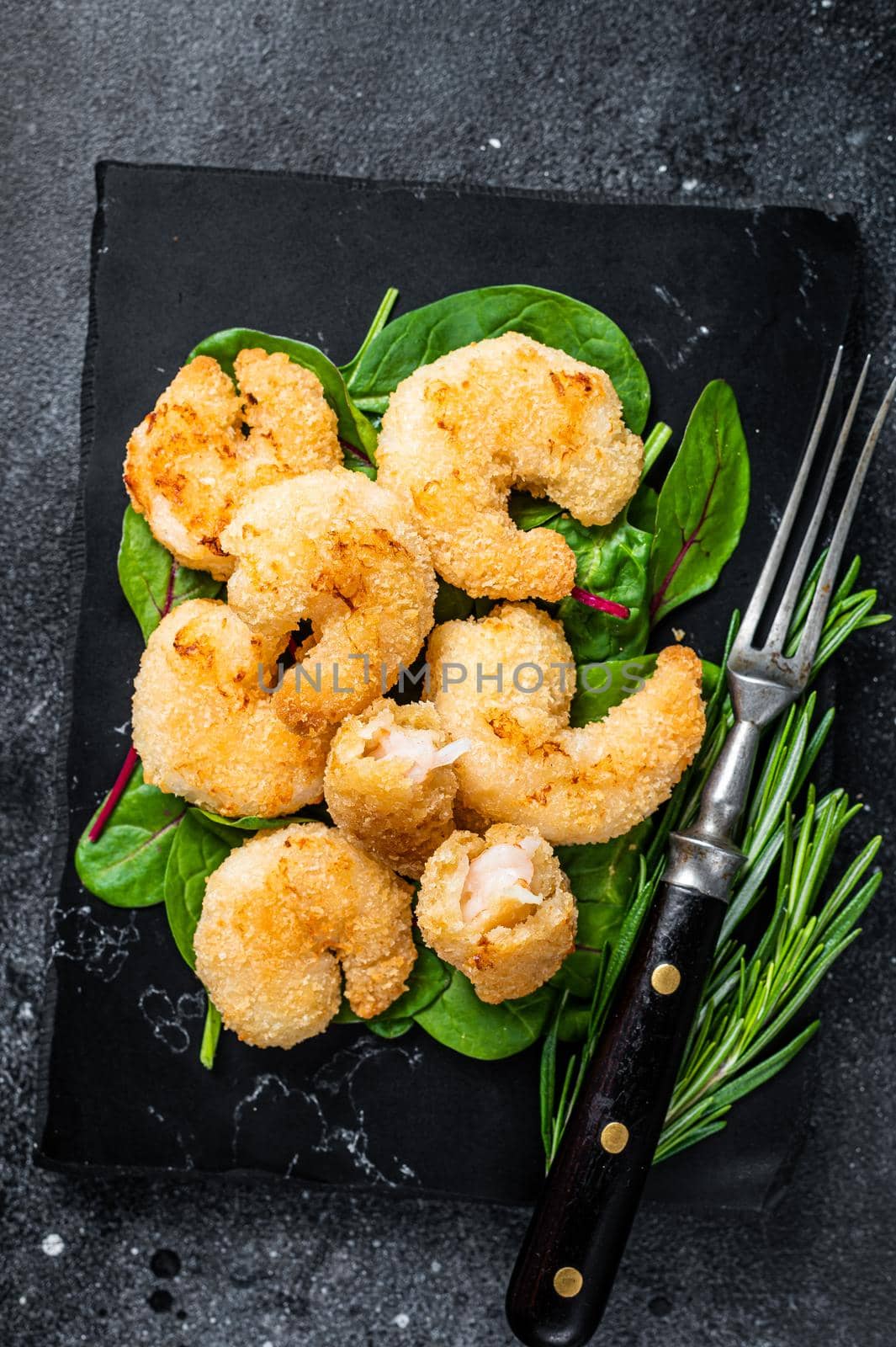 Roasted Crispy Shrimps Prawns on a marble board with green salad. Black background. Top view by Composter