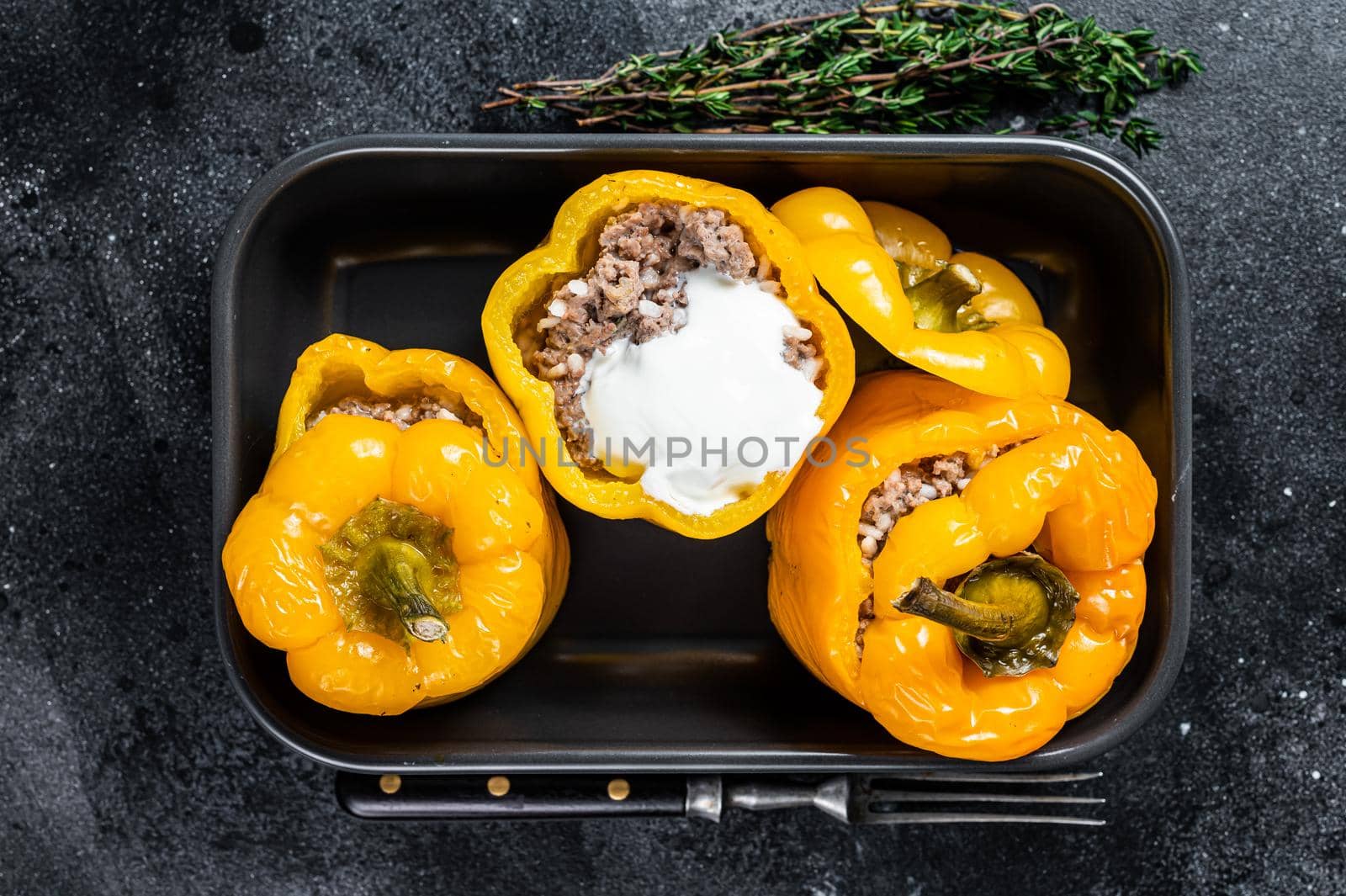 Baked yellow Sweet bell pepper stuffed with beef meat, rice and vegetables. Black background. Top view by Composter