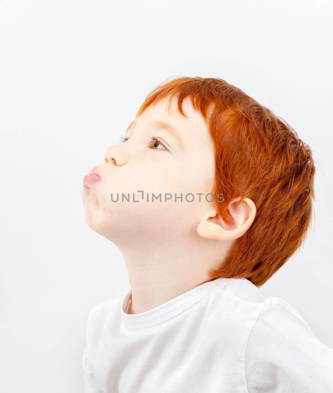 red-haired boy puffed out his cheeks and looks away, closeup