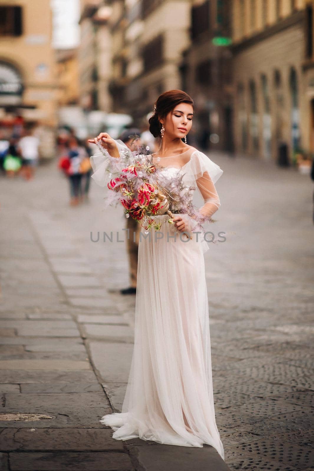 the girl-bride is with beautiful flower pattern as a mask in Florence, stylish bride in a wedding dress standing with a mask in the Old town of Florence. Model girl in Florence.