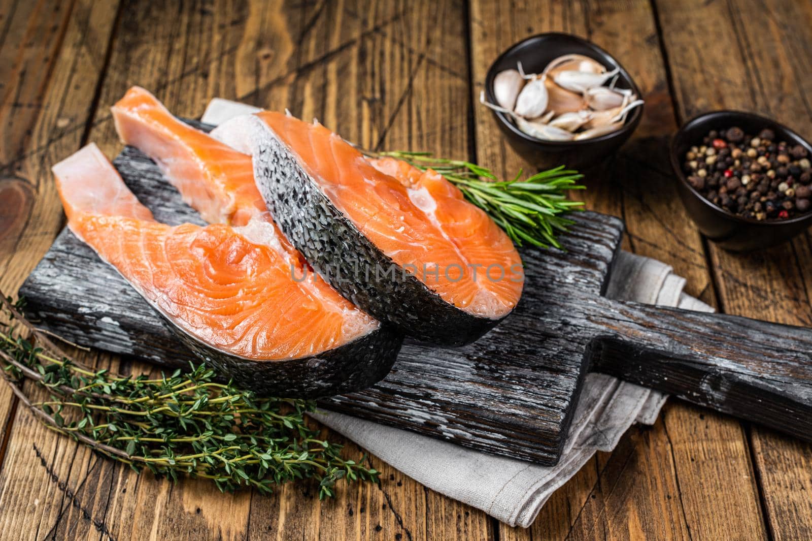 Raw Salmon steaks on a wooden cutting board with thyme and rosemary. wooden background. Top view.