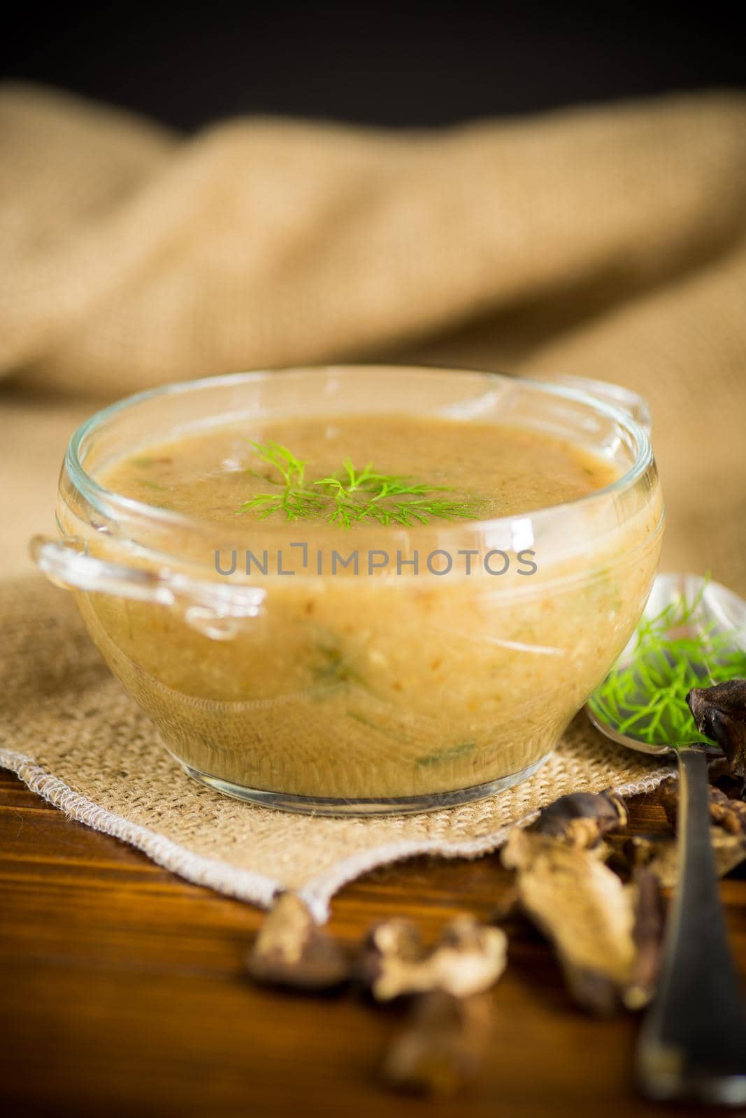 hot homemade vegetable vegetarian soup with dried mushrooms in a glass bowl on a wooden table