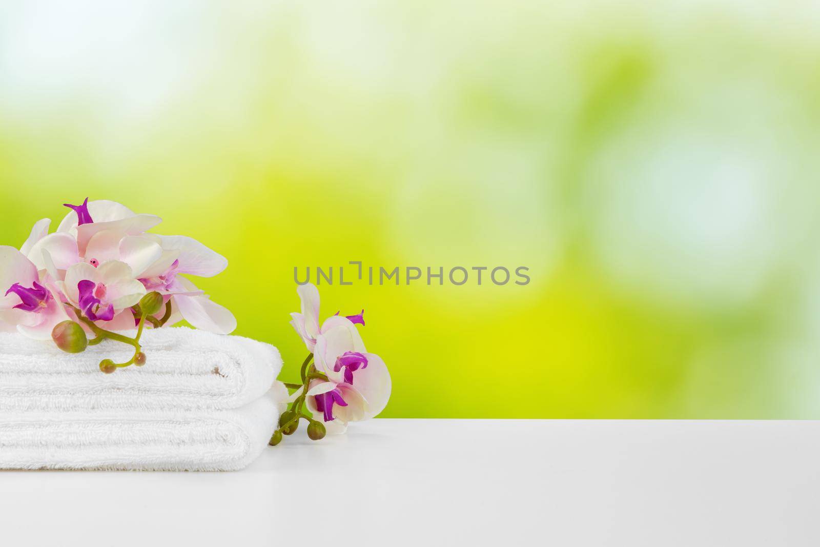 Towels with flowers on light table against blurred background, front view