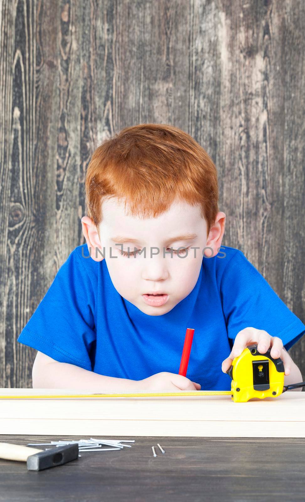 child is engaged in the construction of wooden products in the classroom; close-up portrait of a child with a slight face processing
