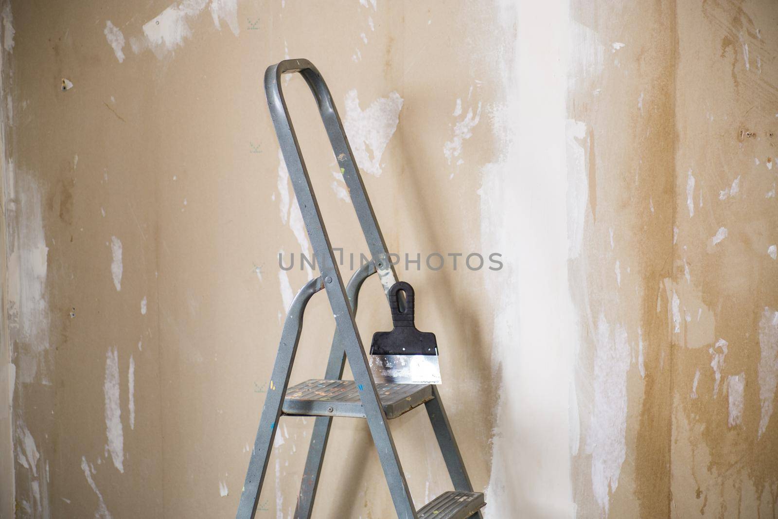 old stepladder on the background of plastered walls before renovation