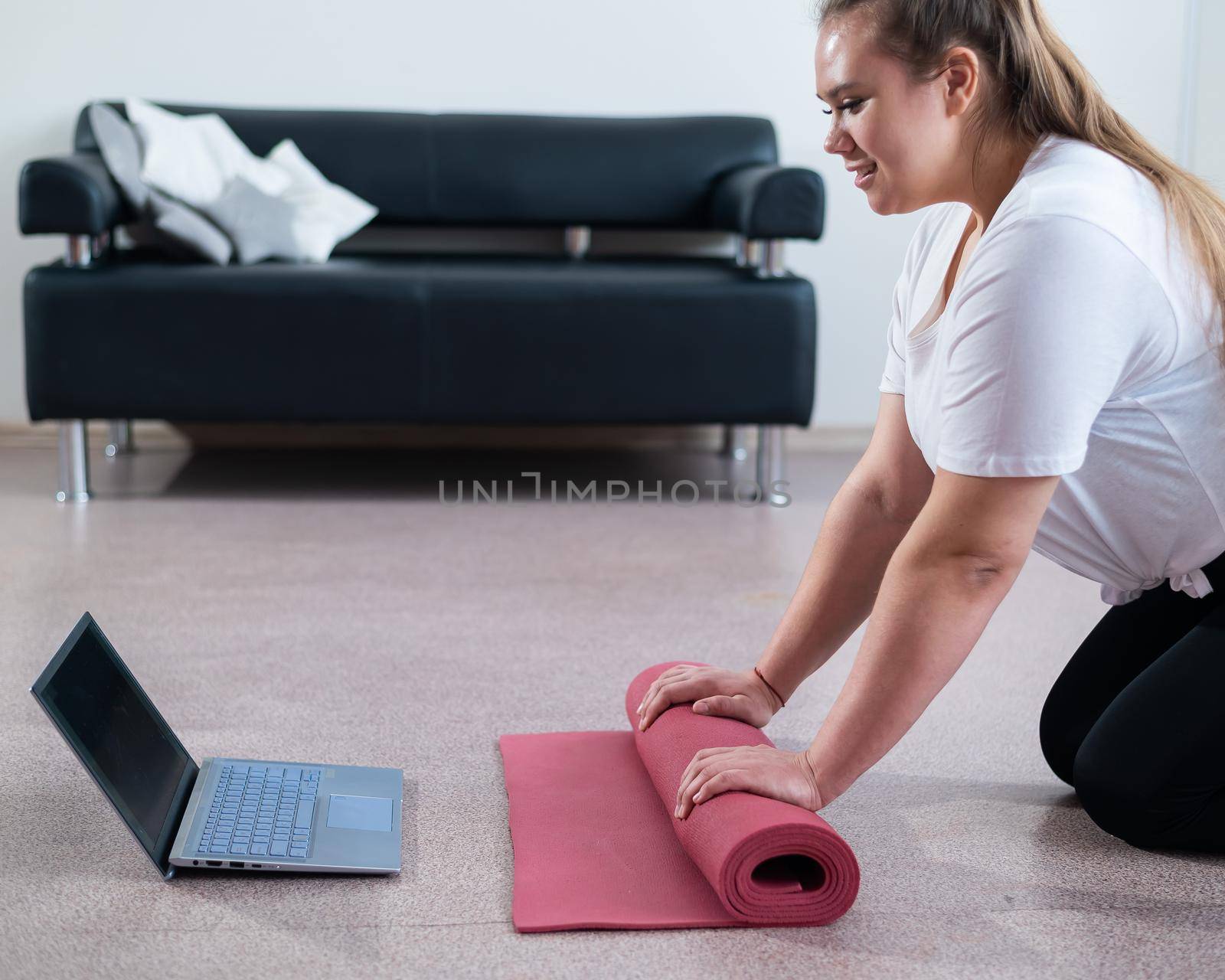 Young chubby woman preparing for an online fitness class. Distance training during the quarantine period.