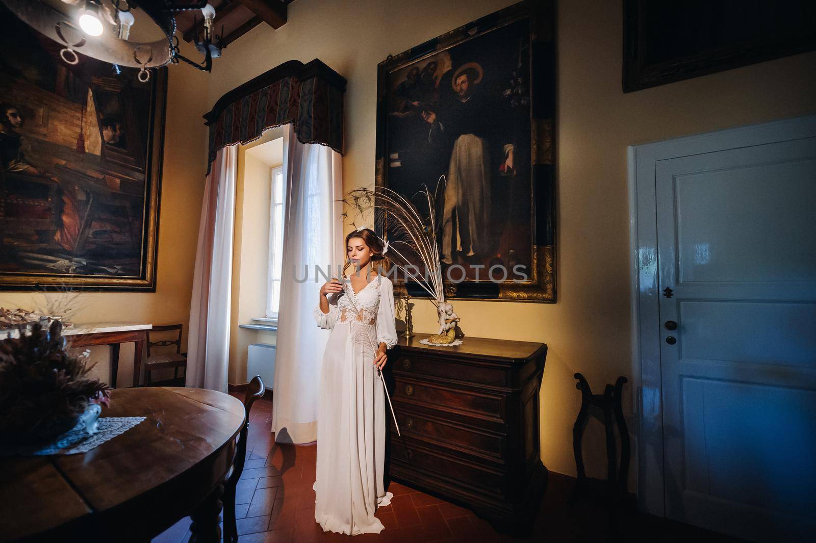 a bride in underwear and a white robe in the interior of a Villa in Italy at a wedding.morning of the bride in Tuscany.boudoir photo session at the Villa