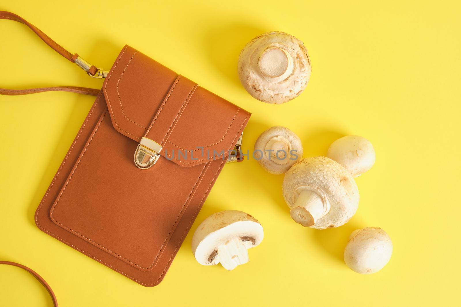 brown bag made of eco leather and champignons on a yellow background, mycelium leather concept, natural alternative materials for making bags, belts and other wardrobe items, vegan leather