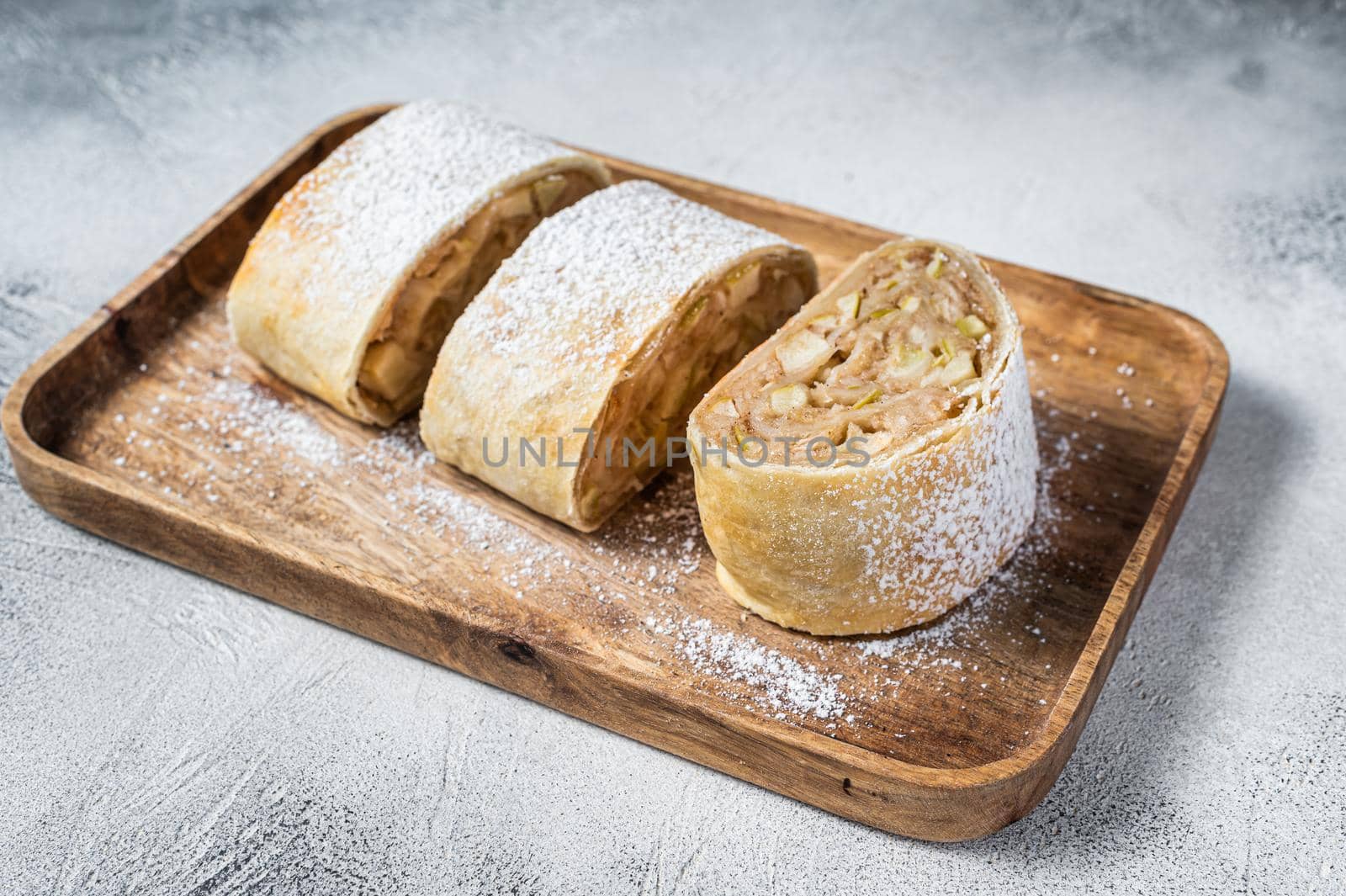 Traditional homemade apple strudel on a wooden tray. White background. Top view.