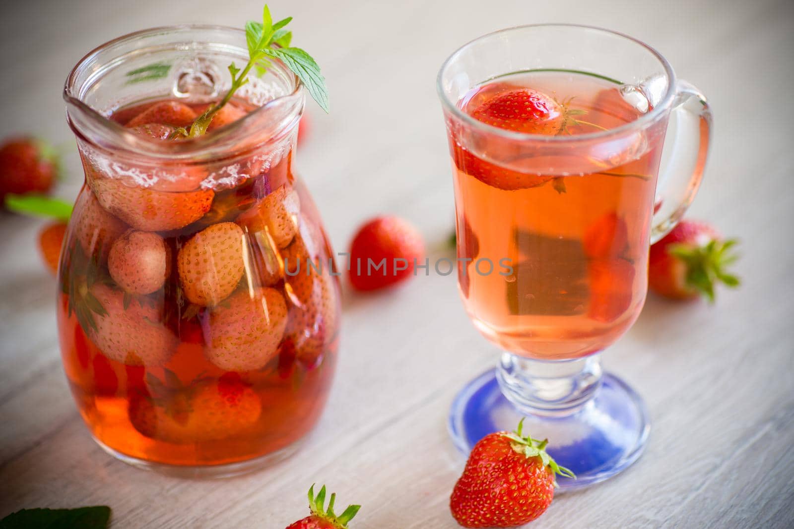 Sweet refreshing berry compote of ripe strawberries in a decanter on a wooden table