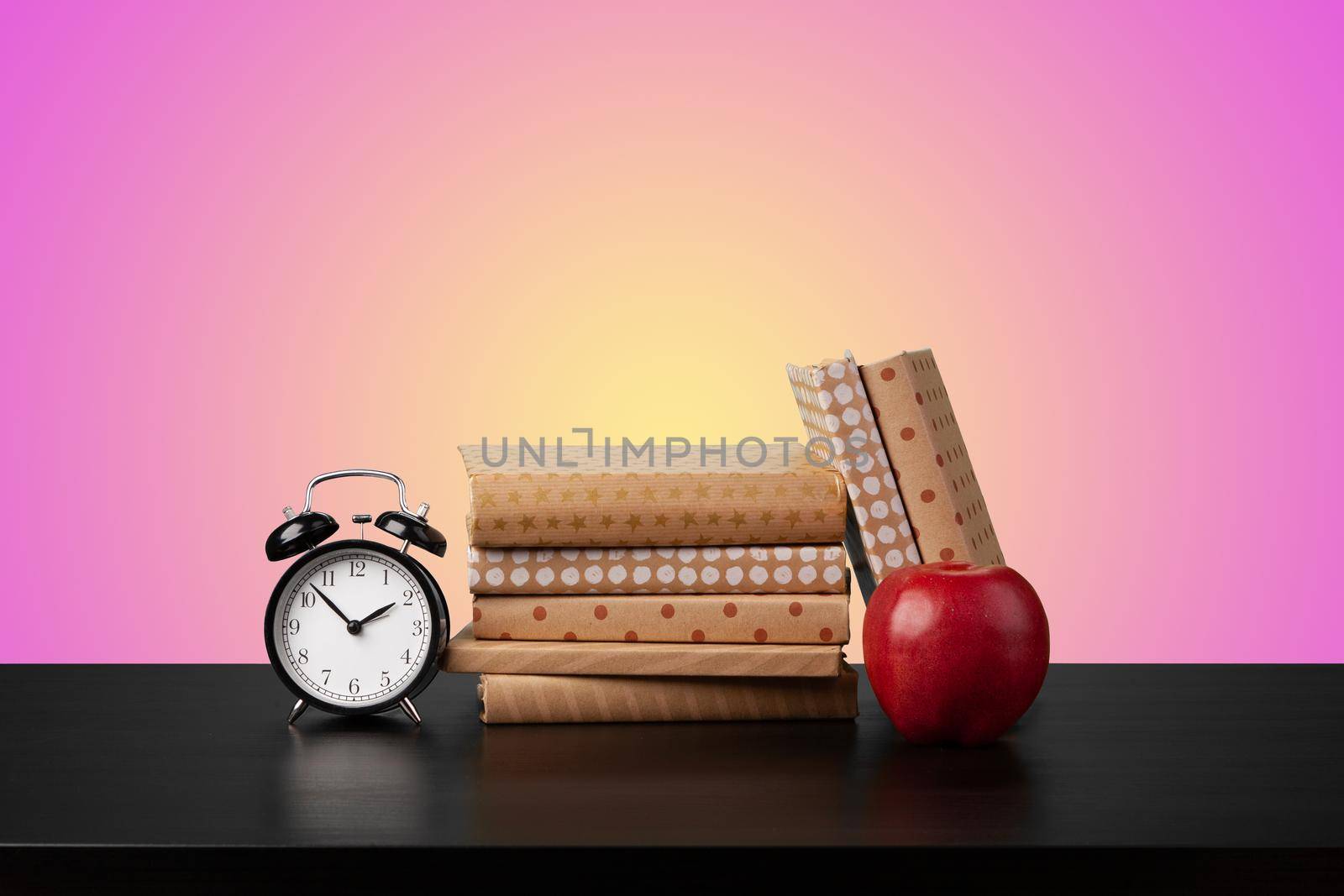 Education concept with stack of books on a table against colored background, front view