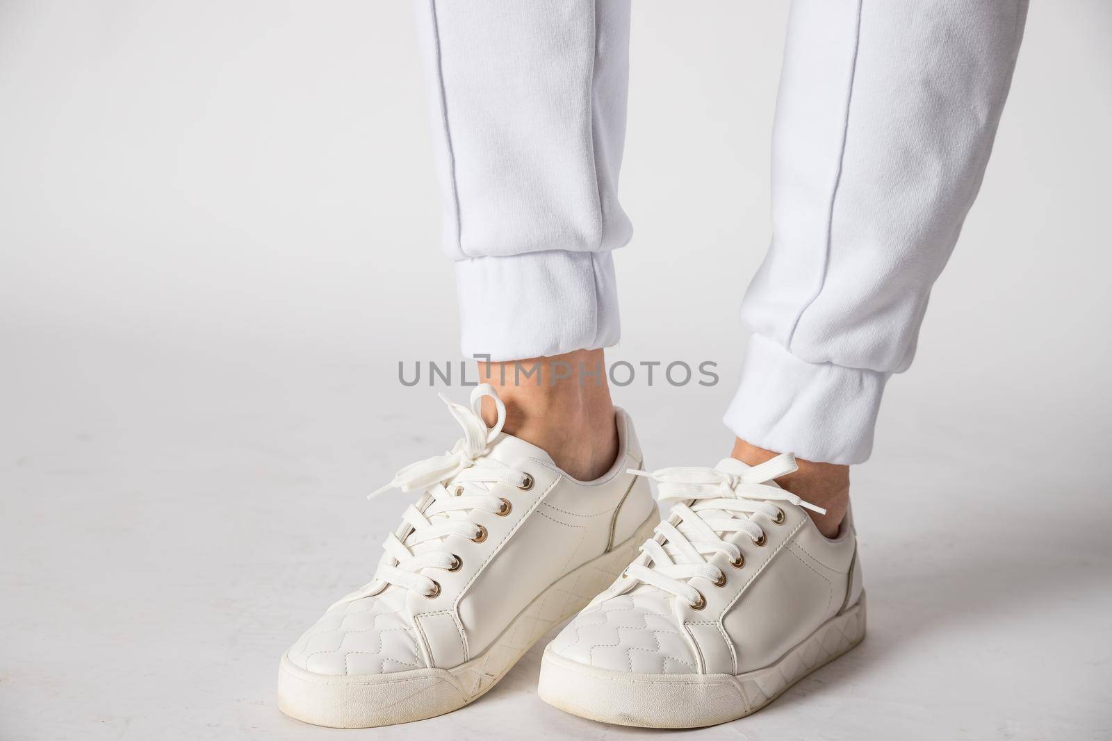 Fashionable women's white leather sneakers. Stylish men's shoes. Casual design. Close-up of male legs.