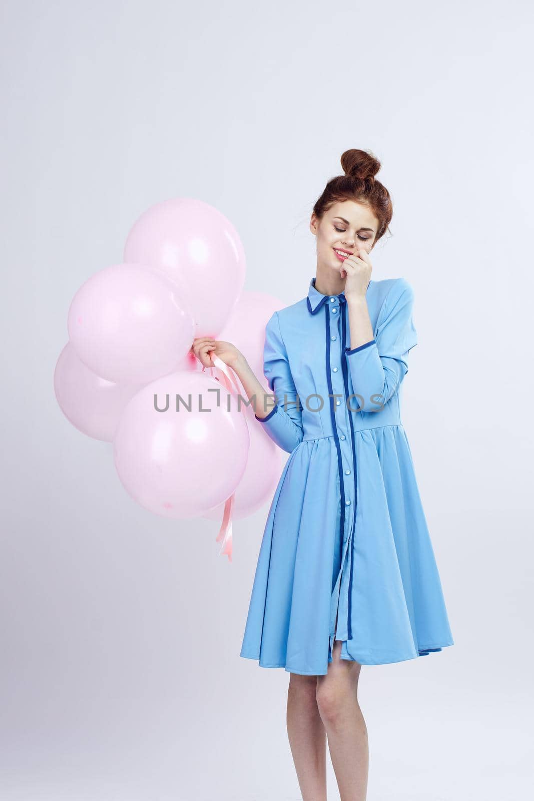 cheerful woman in a blue dress pink balloons holiday birthday. High quality photo