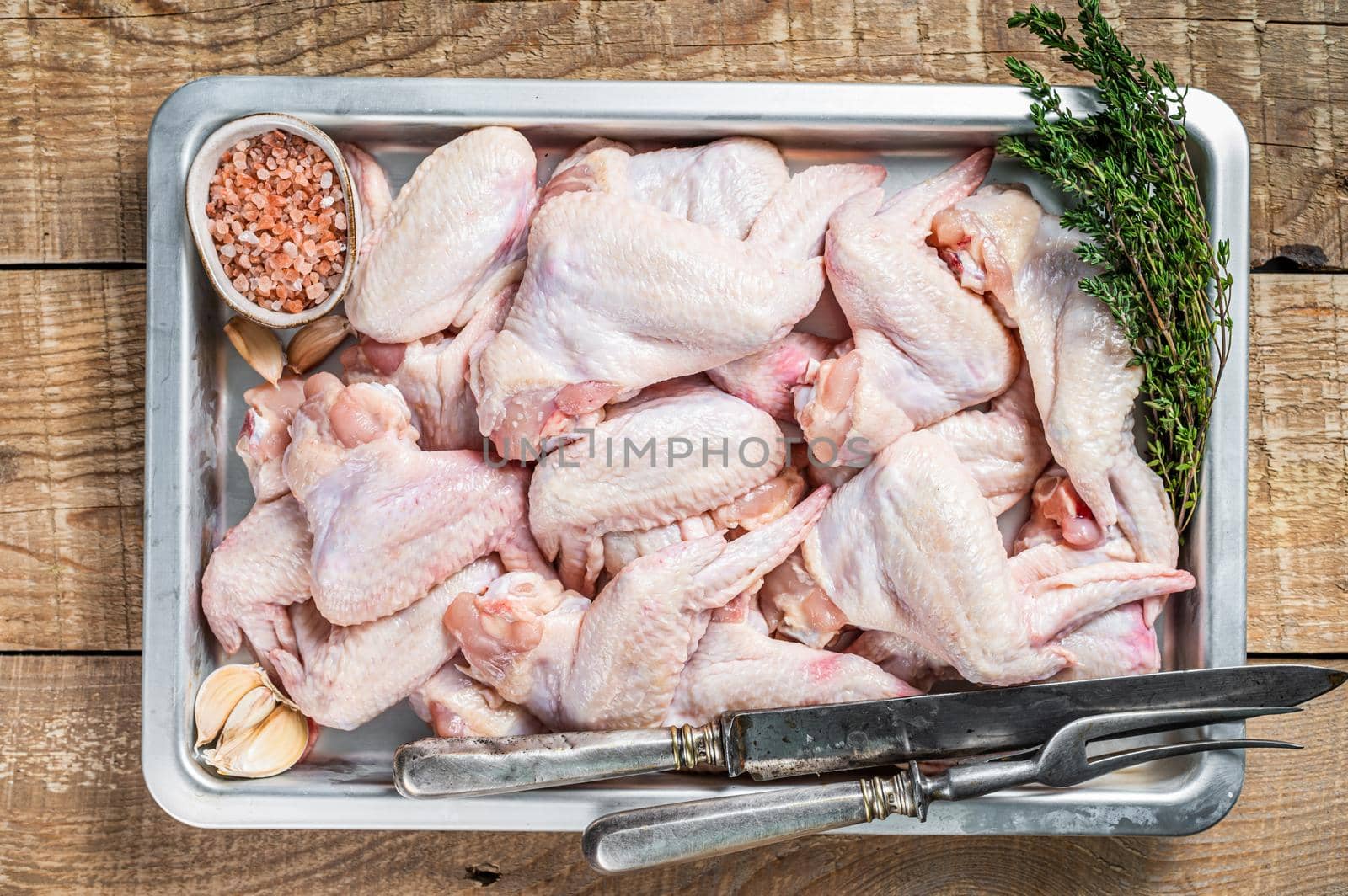 Fresh Raw chicken wings Poultry meat in a kitchen tray with herbs. Wooden background. Top view by Composter