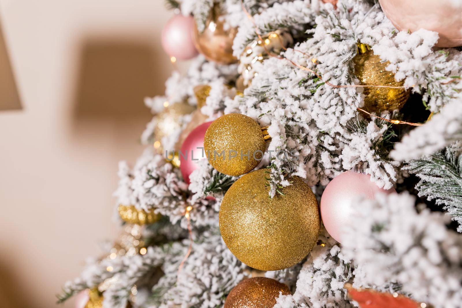 Christmas tree decorated with toys in silver and pink color. In it we see the balloons with of ribbons, stick figure deer, beads