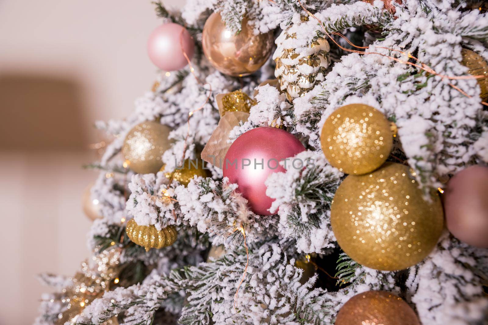 Christmas tree decorated with toys in silver and pink color. In it we see the balloons with of ribbons, stick figure deer, beads