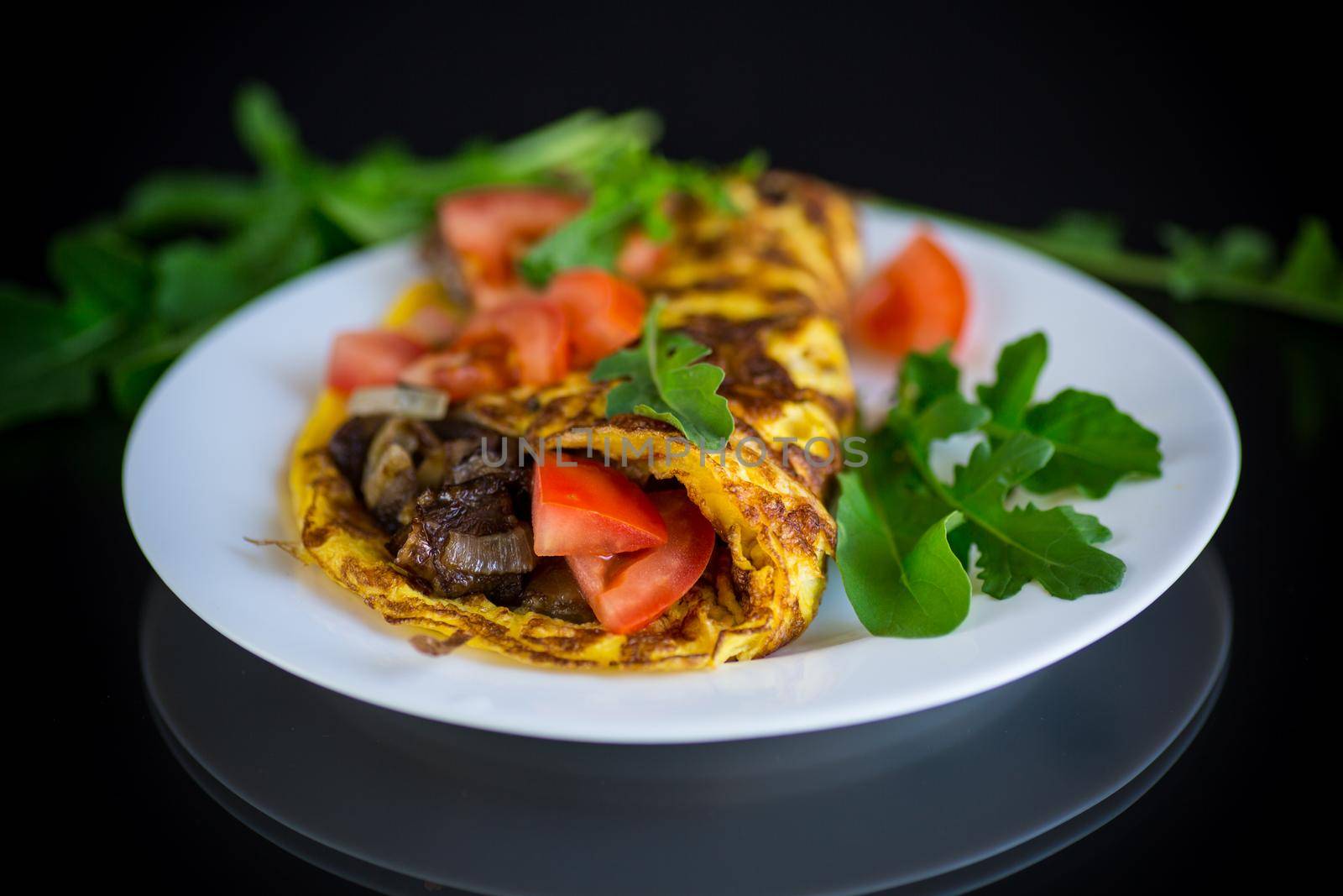fried egg omelet with wild mushrooms and tomatoes, on black background