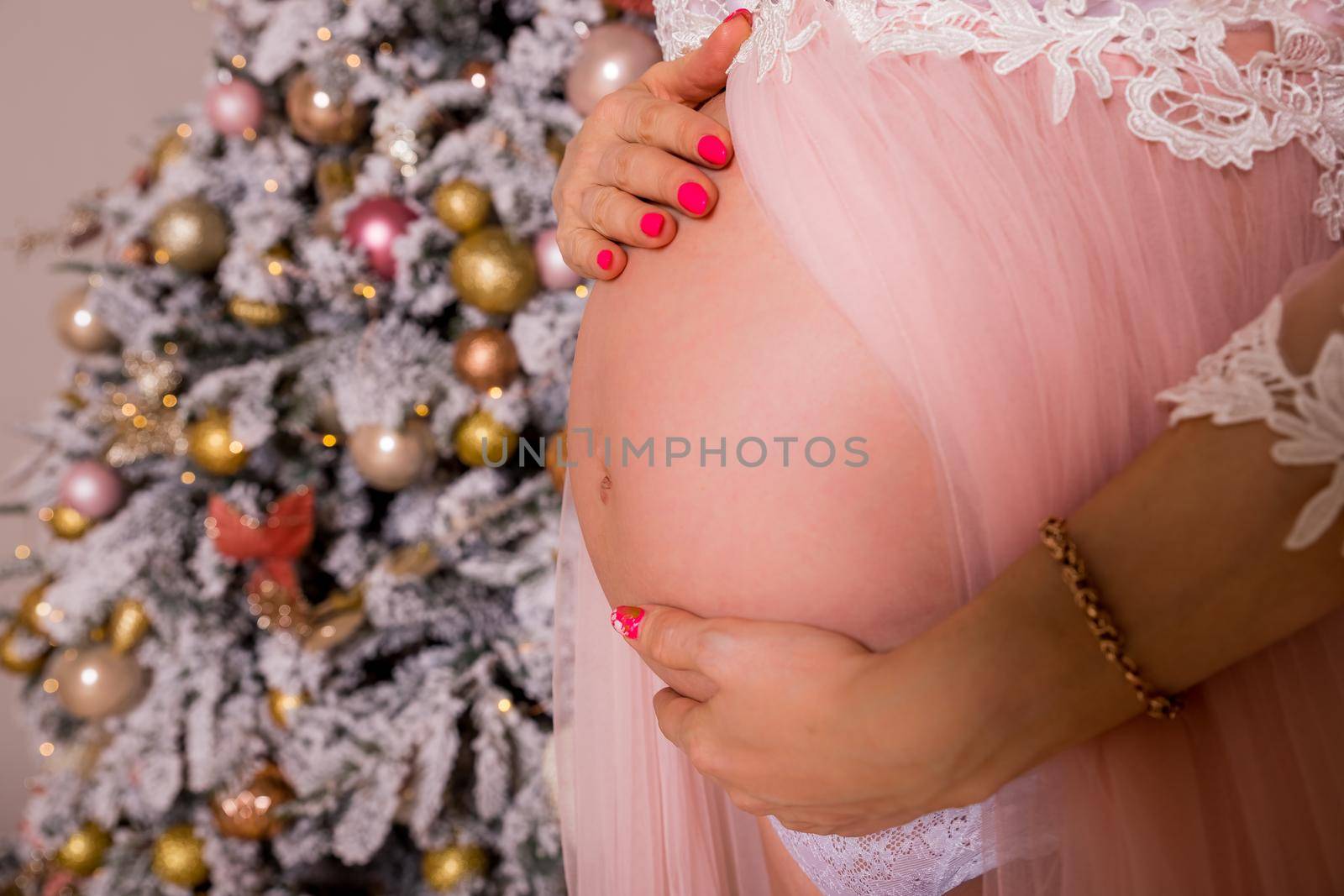 pregnant woman near Christmas tree. belly closeup