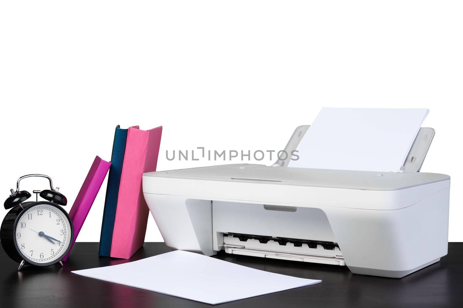 Printer and stack of books on black table against white background, close up