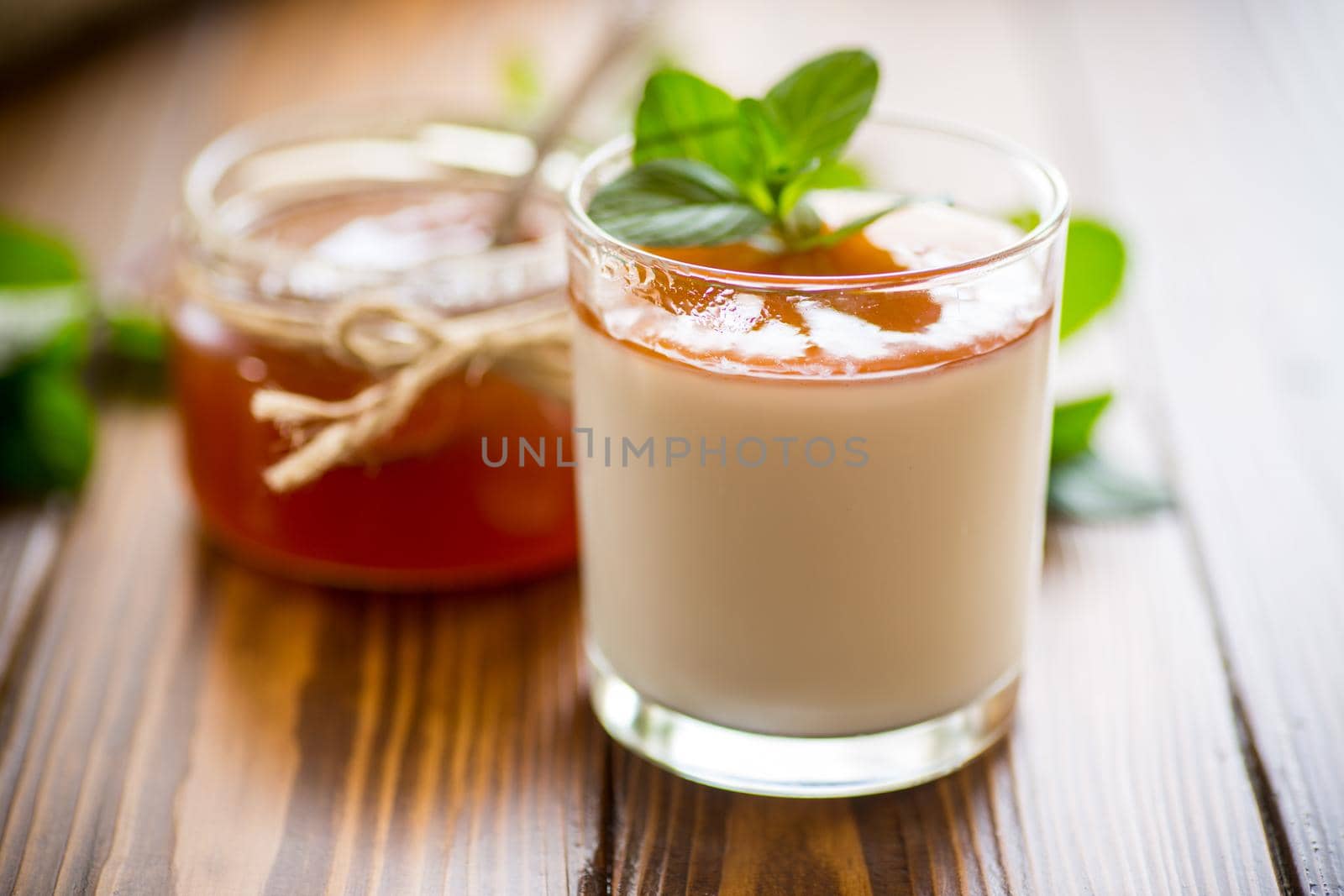 homemade yogurt in a glass and with jam on a wooden table