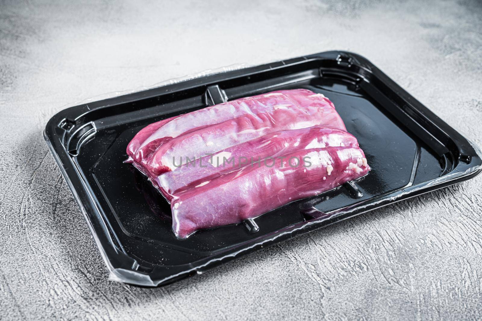 Raw lamb tenderloin in vacuum packaging. White background. Top view.