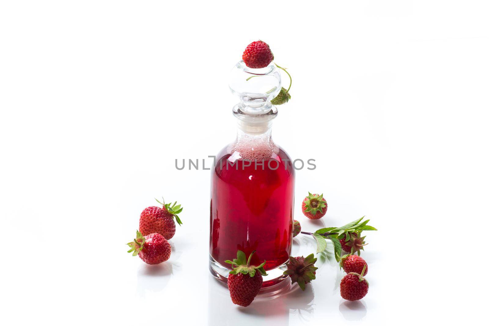 sweet cooked strawberry syrup in a glass decanter isolated on white background