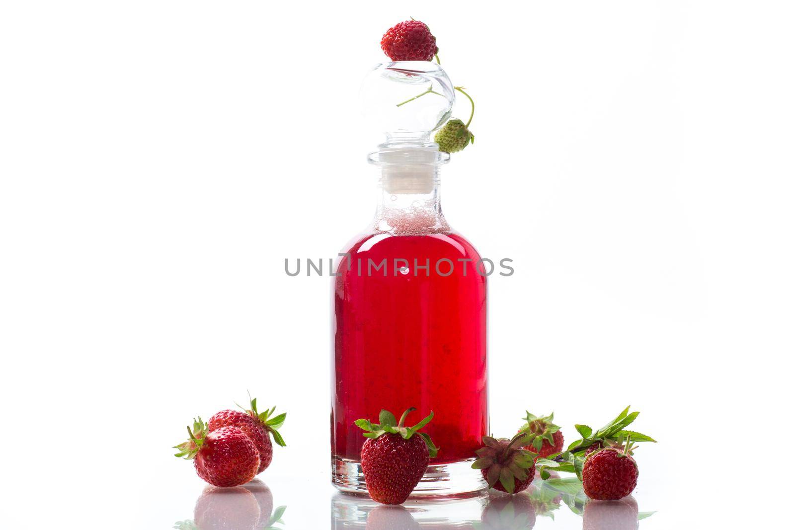sweet cooked strawberry syrup in a glass decanter isolated on white background