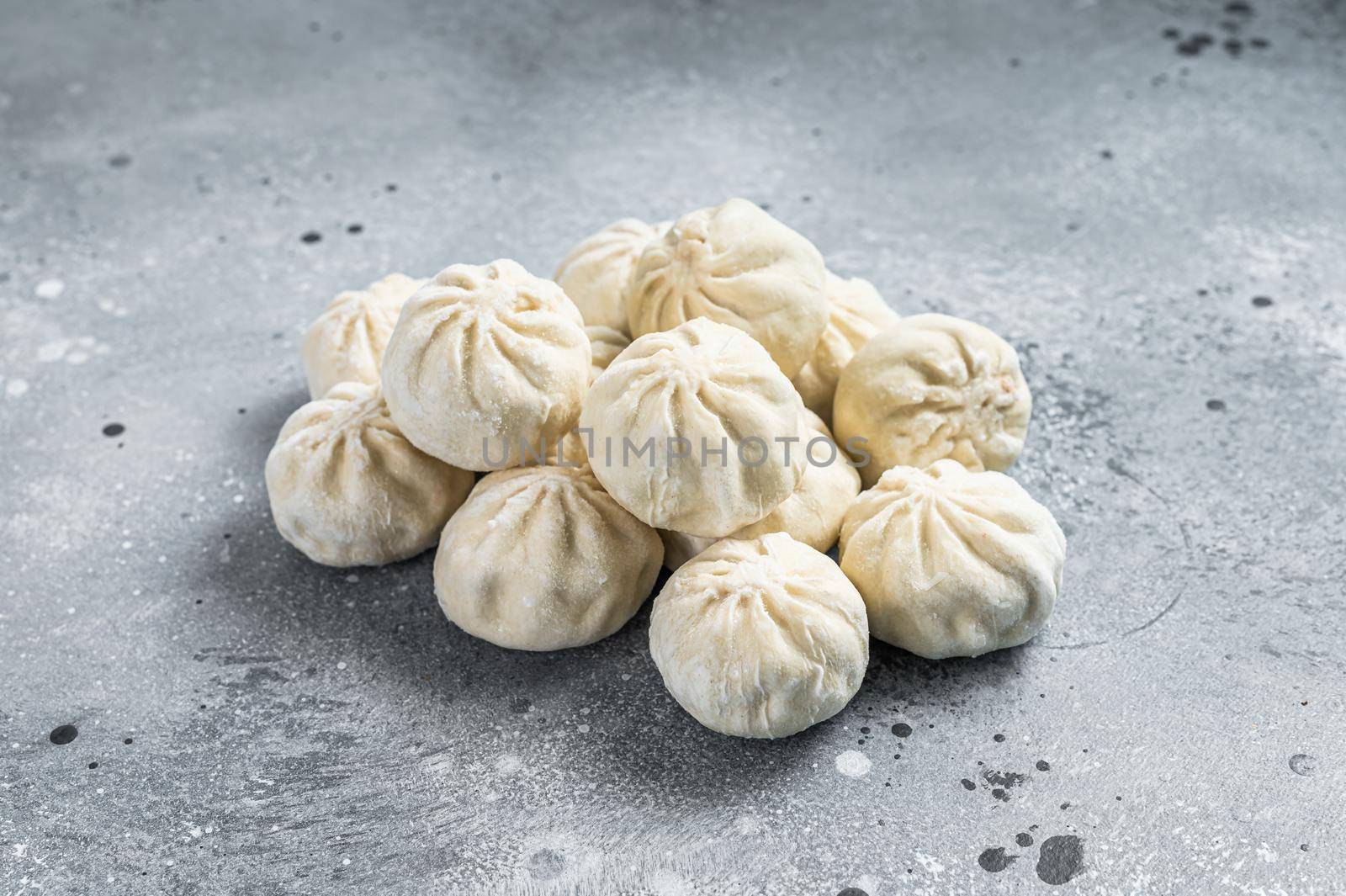 Frozen uncooked baozi dumplings stuffed with meat. Gray background. Top view.