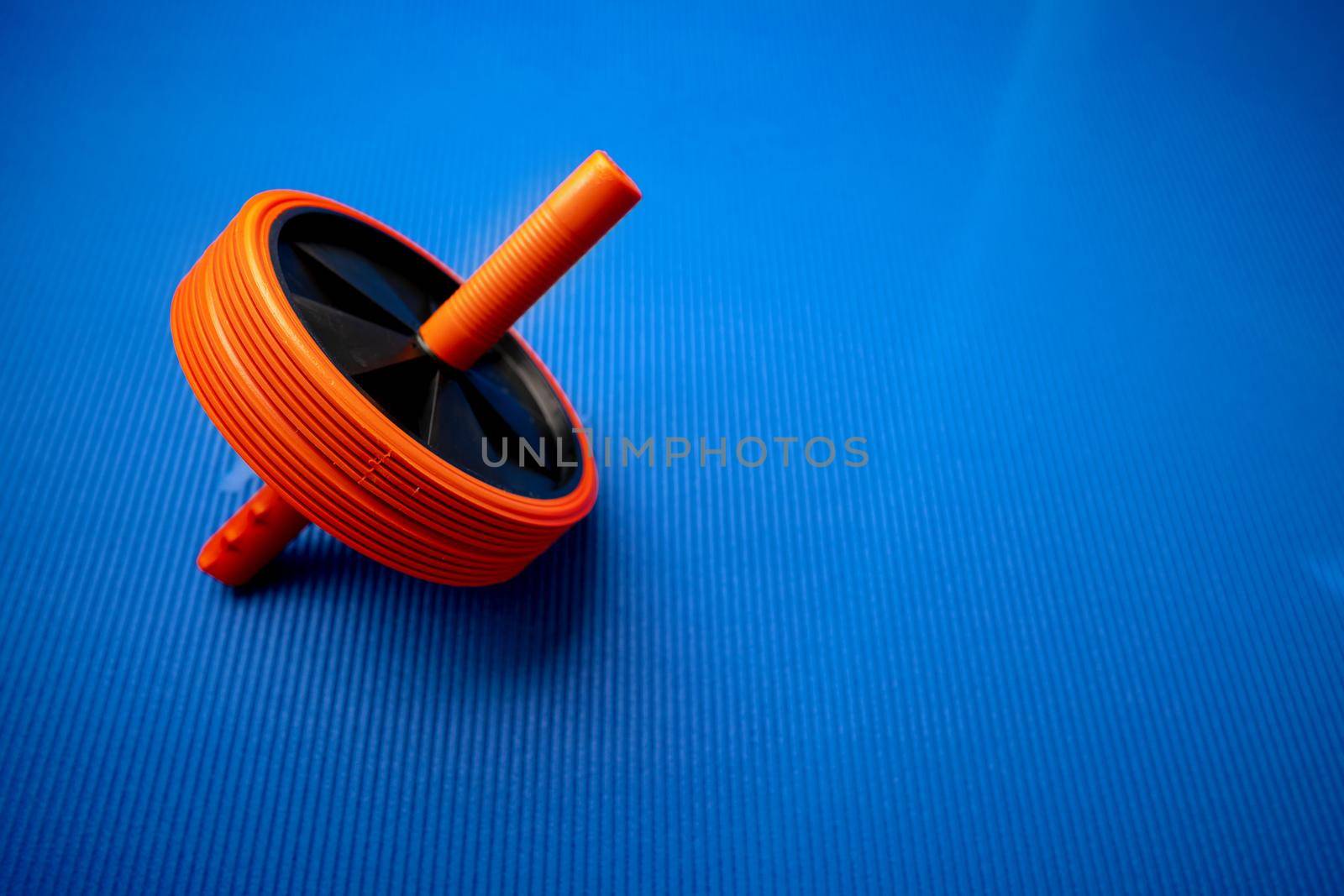 Abs roll out exercise fitness wheel on blue background, close up