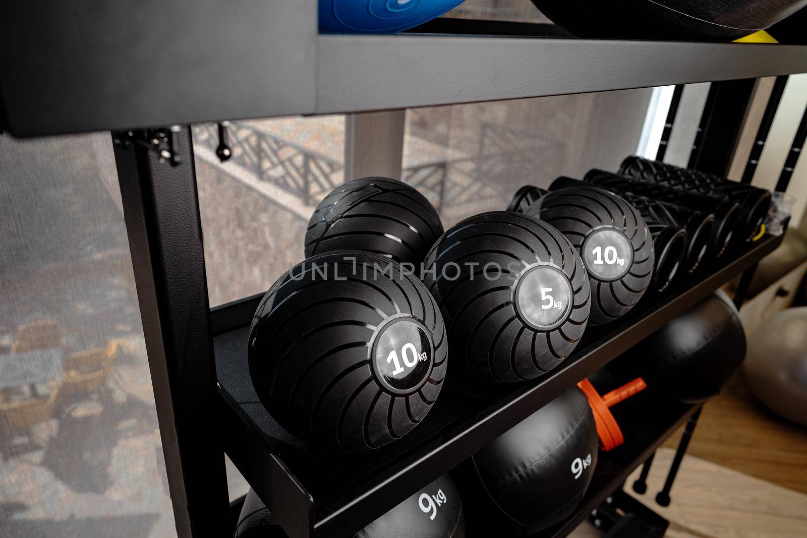 Balls and foam roller sport equipment in a gym on shelf
