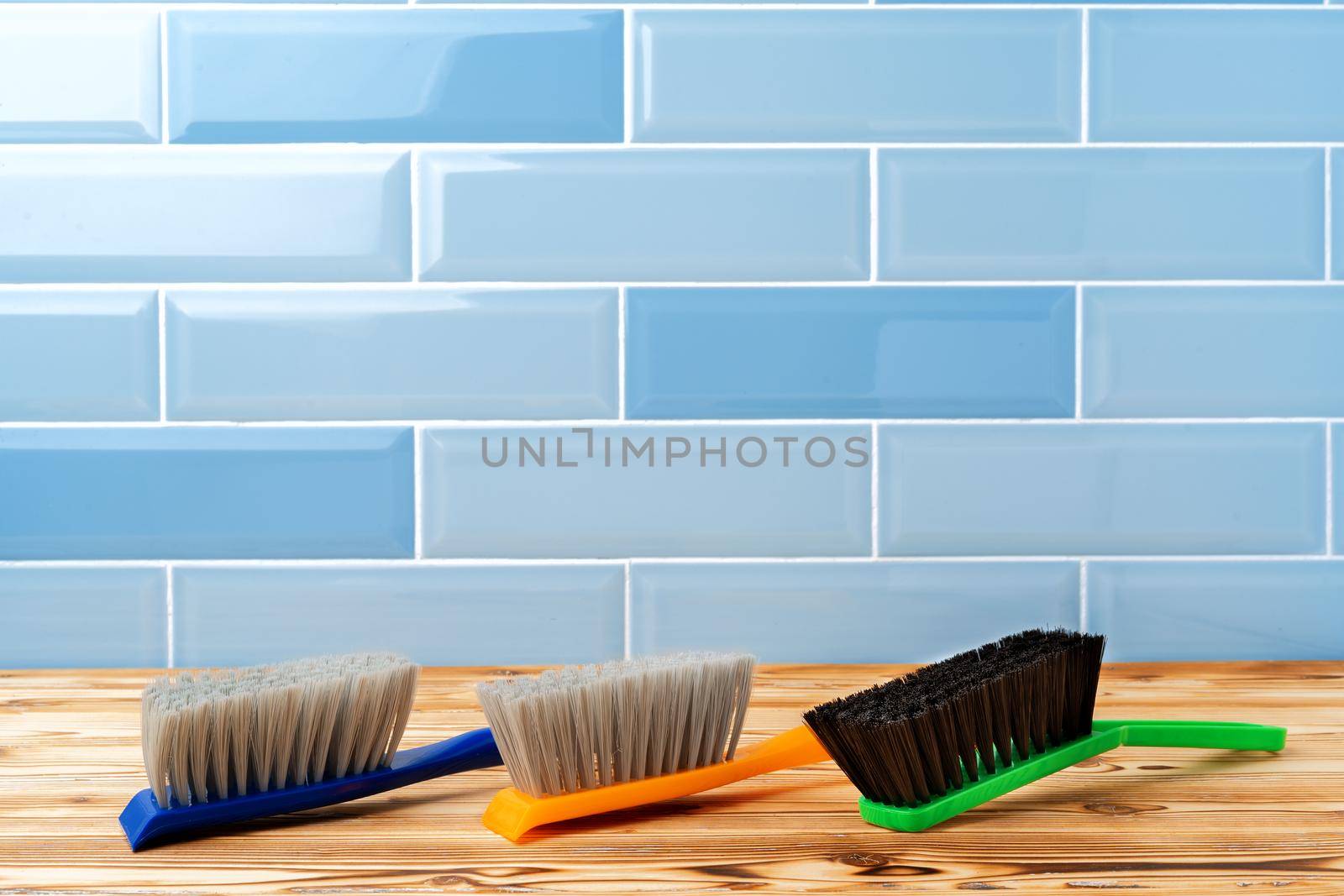 Dust cleaning brushes on wooden table against tile wall, close up