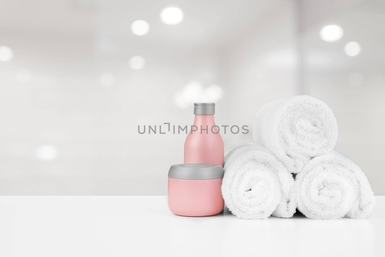 Spa still life with towels and skincare cosmetics against blurred background, close up
