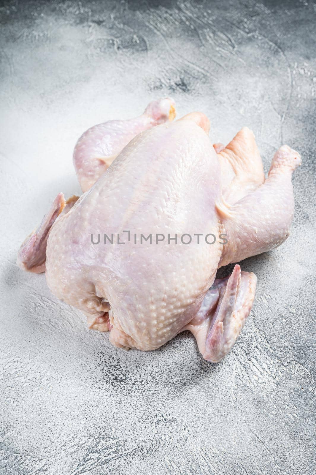 Raw free range whole chicken on a kitchen table. White background. Top view.