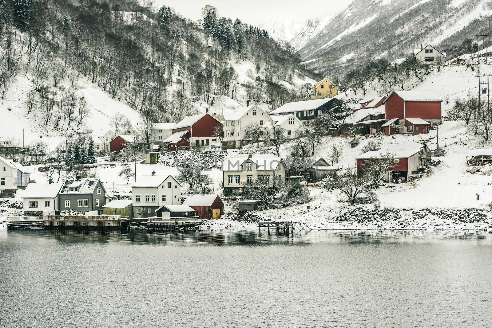 wooden houses on the banks of the Norwegian fjord, beautiful mountain landscape in winter