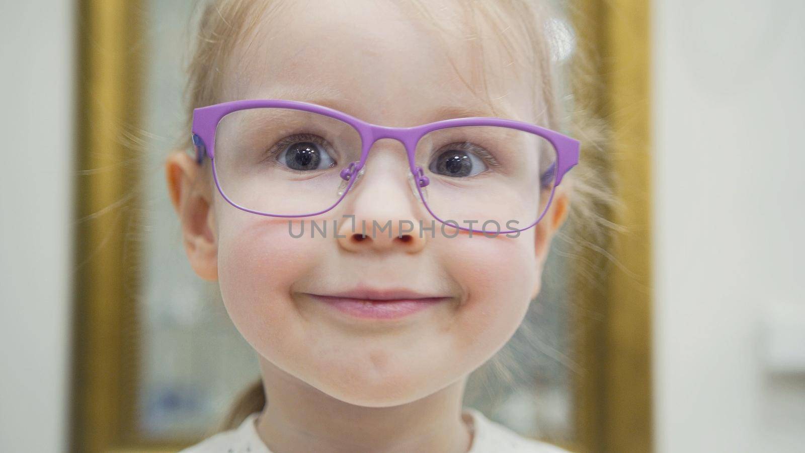 Blonde girl tries fashion medical glasses shopping in ophthalmology clinic - portrait, close up