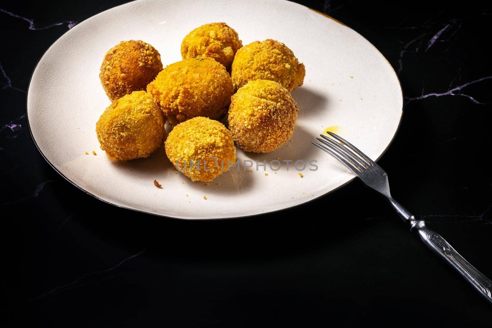 cheese balls with garlic and dill inside for a snack in a plate on a black background.