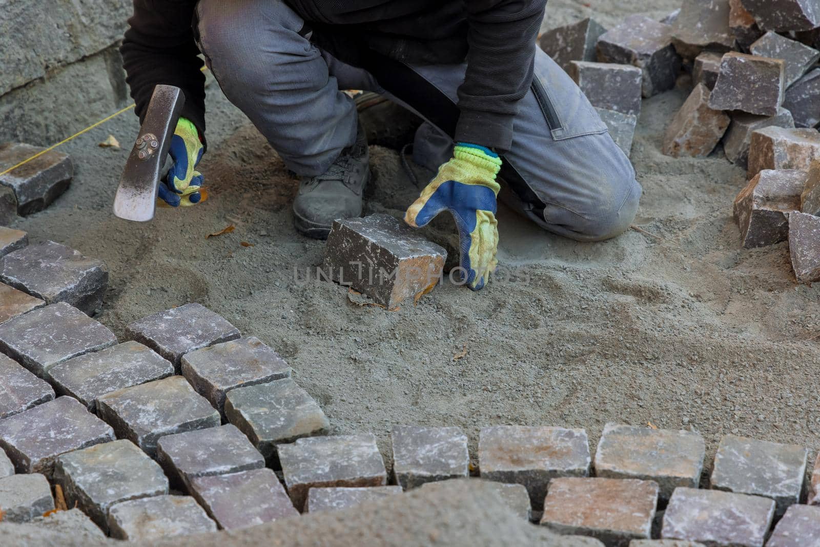 Construction worker installing stone on road is putting down pavers during a construction by ungvar