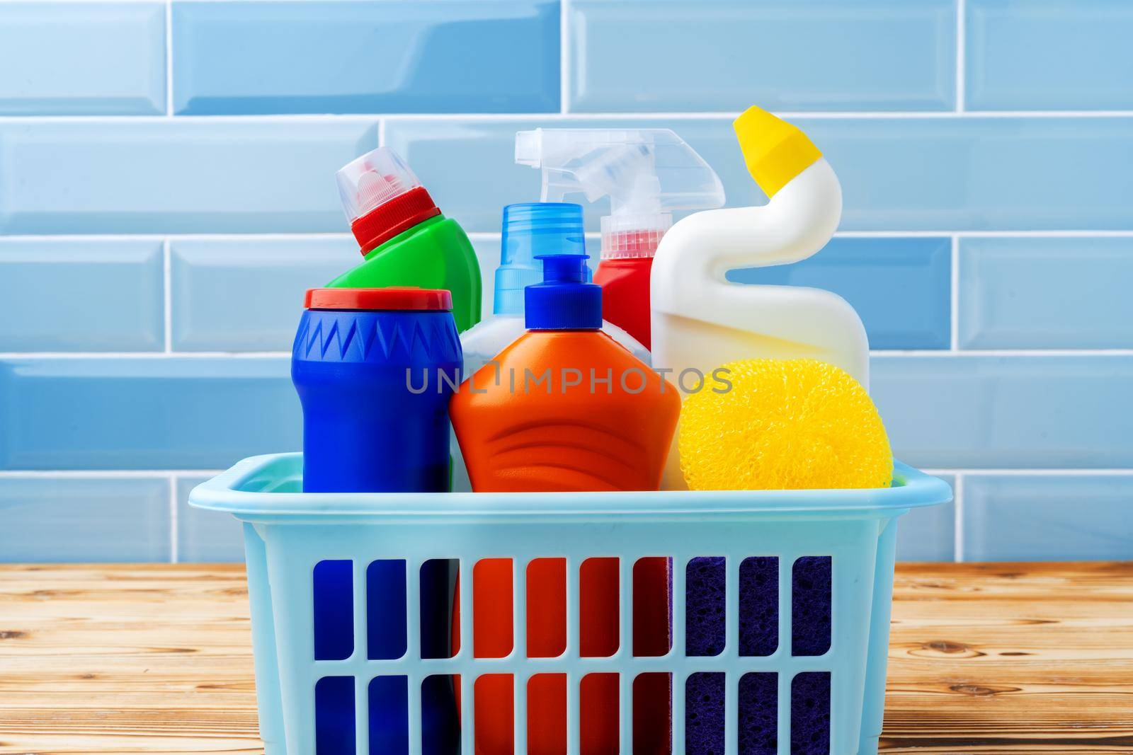 Household detergents and cleaning tools against blue tile background, close up