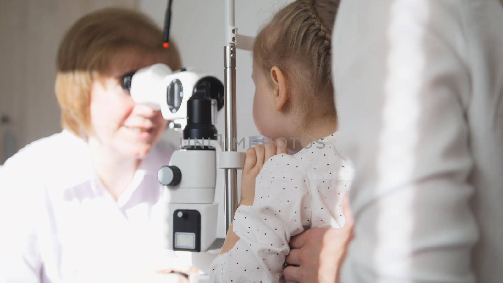 Little girl and her mommy in ophthalmology - optometrist checking little child's vision by Studia72