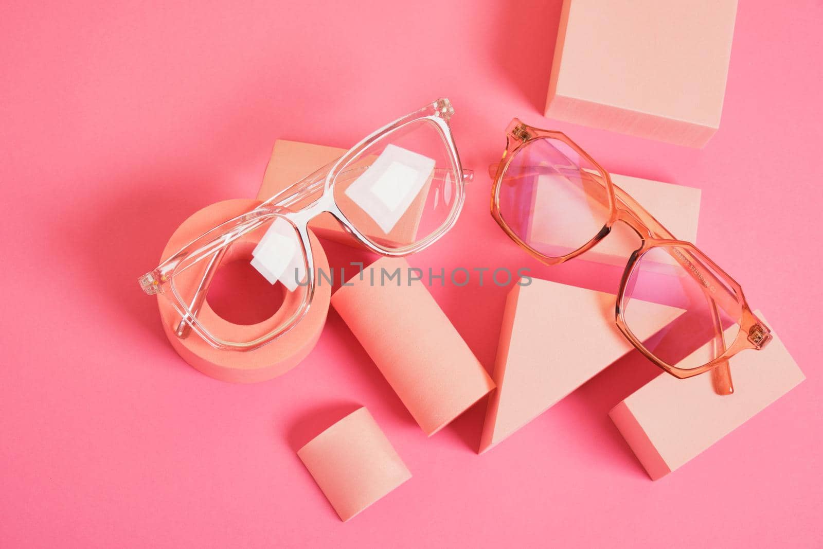 trendy eye glasses on geometric pink podiums, colorful background, copy space by natashko