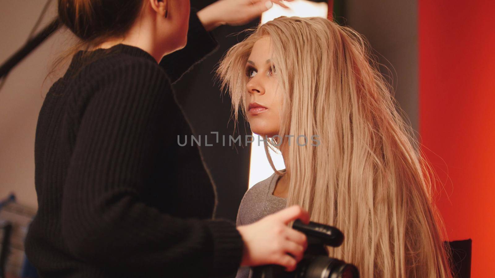 Blonde white caucasian model girl in photo studio - photographer straightens hair, fashion backstage by Studia72