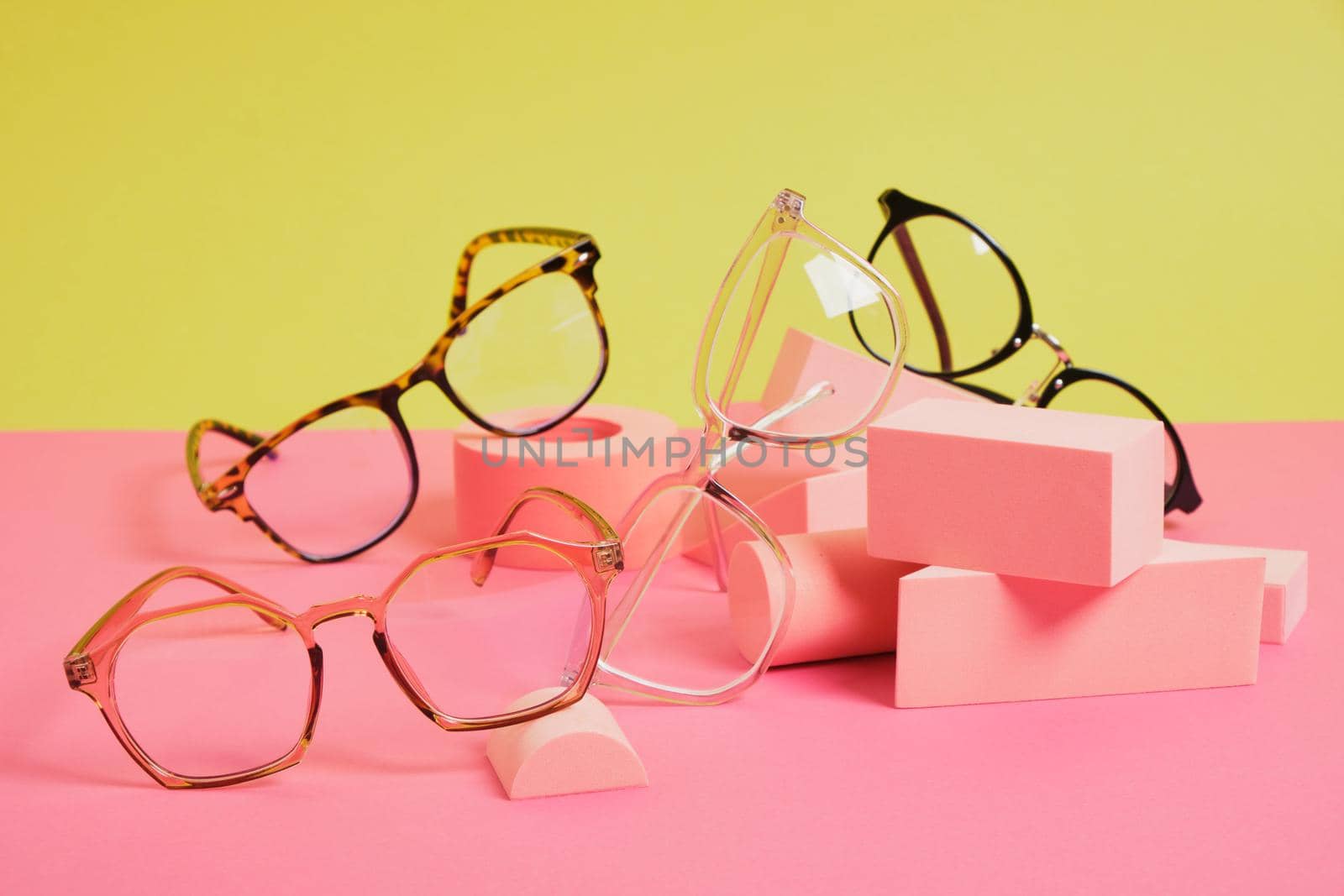 several different trendy eye glasses on geometric pink podiums, colorful background, copy space